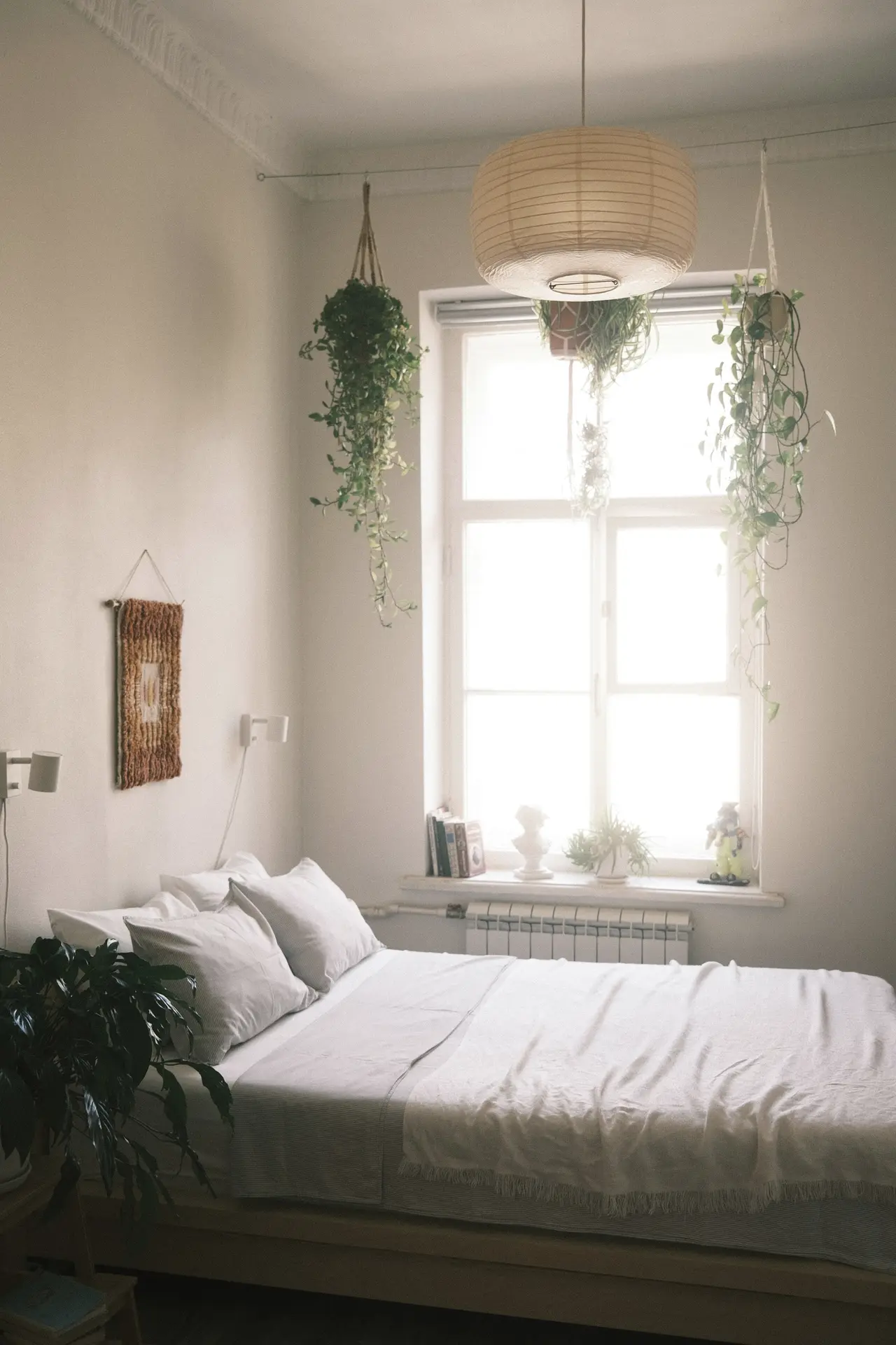 A bright apartment bedroom with a made bed beneath a tall window